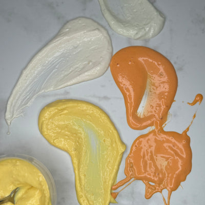 Aioli i olika smaker utsmetad på en marmorskiva. Fotat ovanifrån.