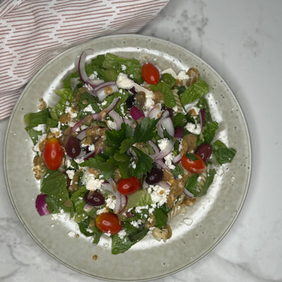 Grekisk sallad upplagd på en tallrik som serveringsförslag. Fotat ovanifrån,