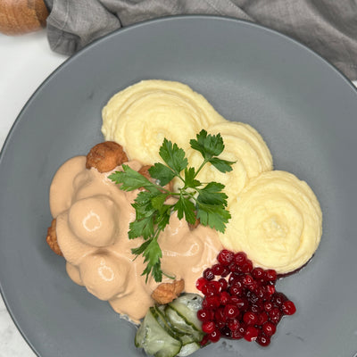 Köttbullar med mos upplagt på en tallrik som ett serveringsförslag. Toppad med persilja.