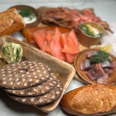 Kustbuffe upplagt på olika fat och marmorskiva som ett serveringsförslag. Man ser flera delar av innehållet i buffén. Fotat från sidan.