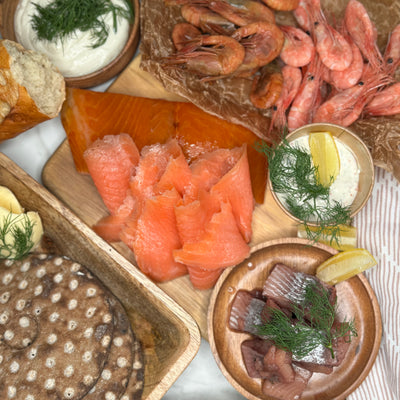 Kustbuffe upplagt på olika fat och marmorskiva som ett serveringsförslag. Man ser flera delar av innehållet i buffén. Fotat ovanifrån.