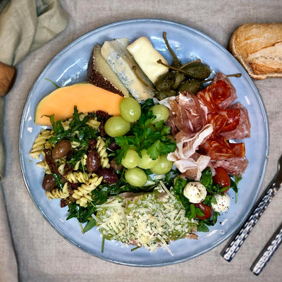 Italiensk buffe upplagt på en tallrik som ett serveringsförslag. Man ser olika delar av buffén upplagd på tallriken. Fotat ovanifrån.