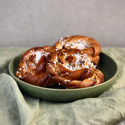 Kanelbullar ligger i tallrik och är fotade från sidan.