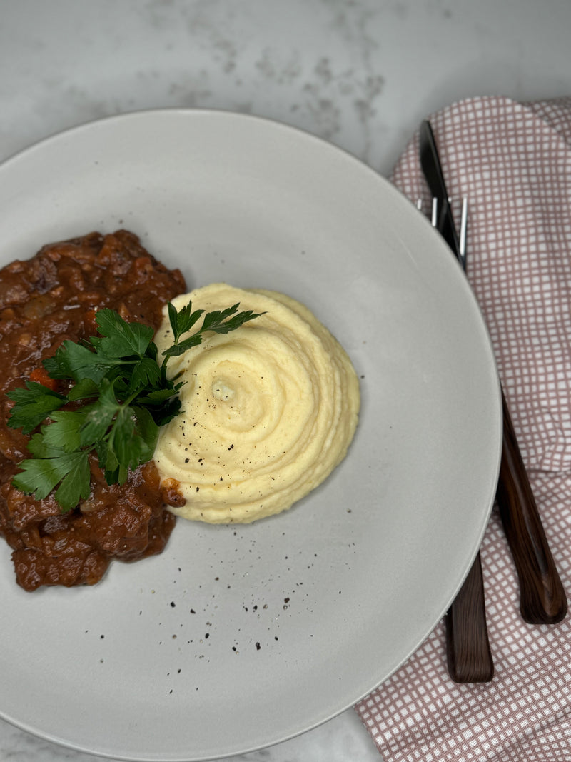 Boeuf Bourguignon upplagt på en tallrik som ett serveringsförslag. Toppad med persilja.