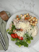 Ceasarsallad med kyckling upplagd på en tallrik som ett serveringsförslag. Fotad ovanifrån 
