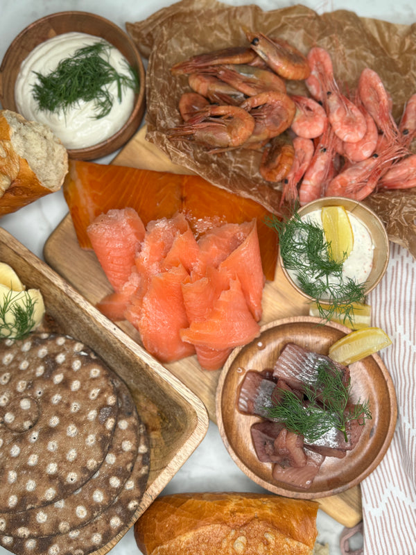 Kustbuffe upplagt på olika fat och marmorskiva som ett serveringsförslag. Man ser flera delar av innehållet i buffén. Fotat ovanifrån.