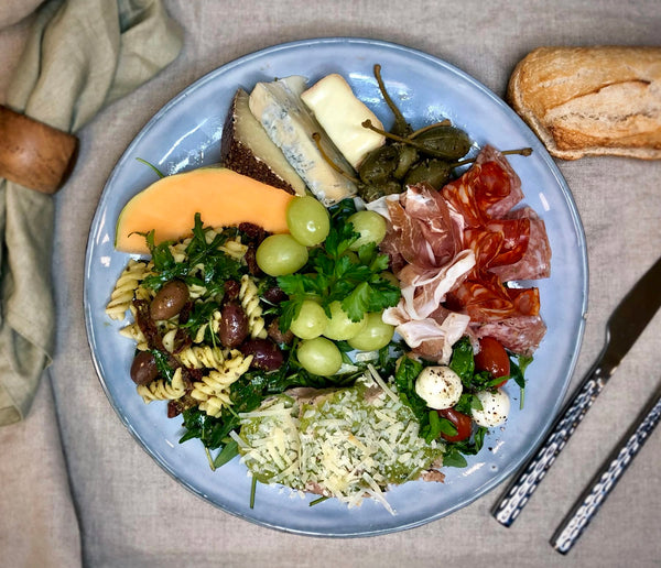 Italiensk buffe upplagt på en tallrik som ett serveringsförslag. Man ser olika delar av buffén upplagd på tallriken. Fotat ovanifrån.