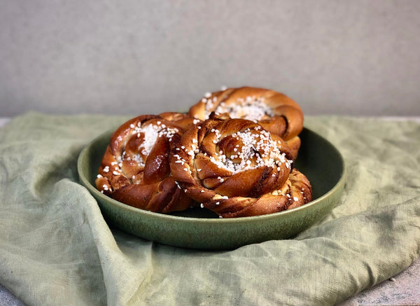 Kanelbullar ligger i tallrik och är fotade från sidan.